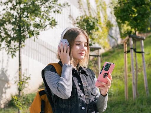 Kurzhaarige Frau mit Kopfhörern, die auf ihr Handy schaut.